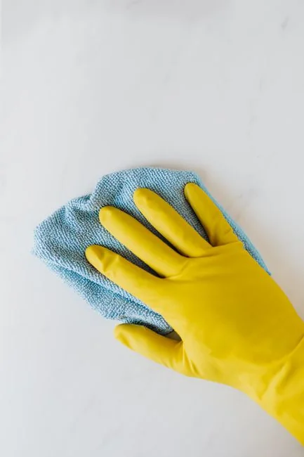 A man is cleaning a glass door indoors with a spray bottle and cloth.